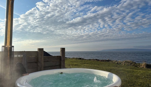 At the edge of the sea, this stunning house has a wood fired hot tub.
